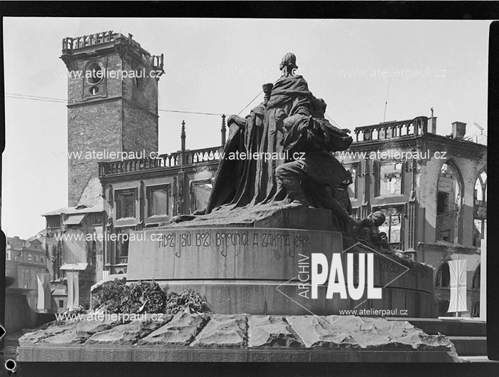 Husův pomník s vyhořelou Staroměstskou radnicí